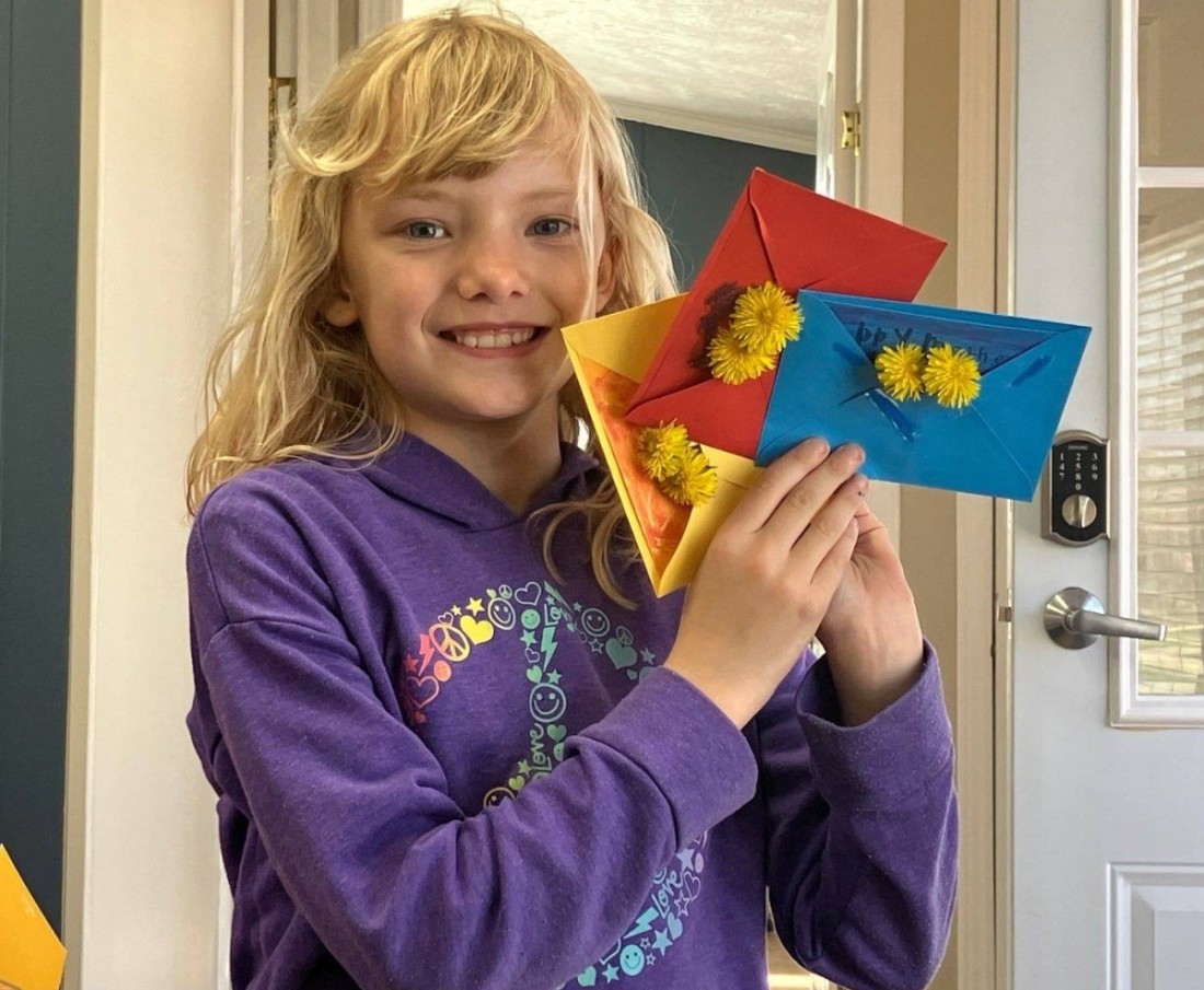 A young girl holds cards she made for Mother's Day