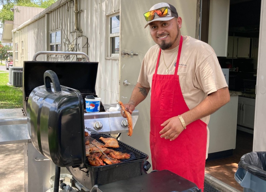 A Bayshore resident cooks BBQ on a grill at a summer community event
