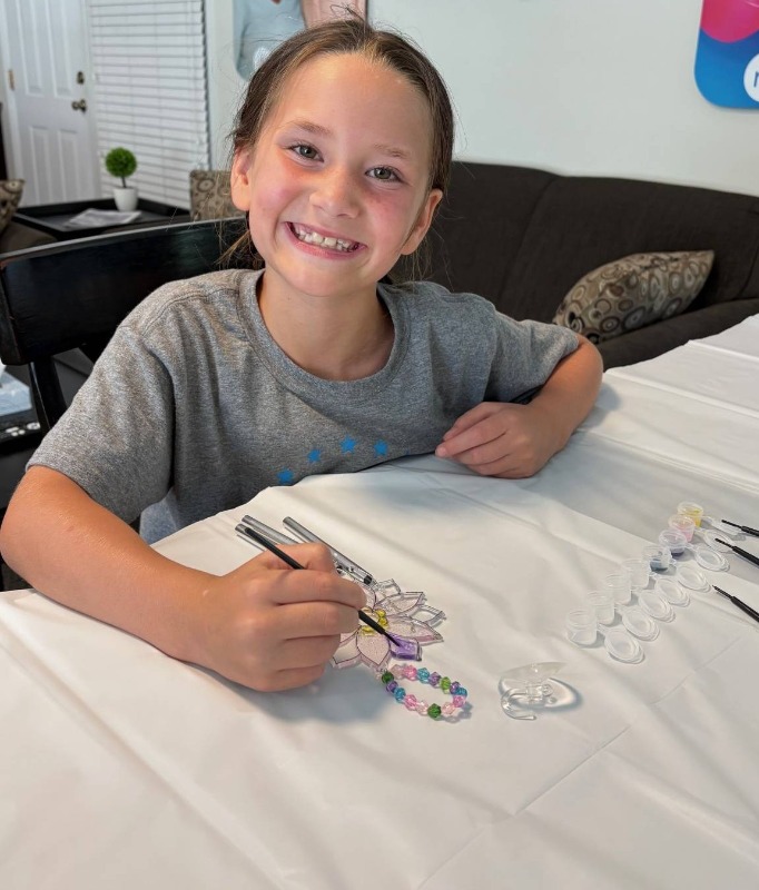 A young girl smiles while playing at the crafting table during a Bayshore community event