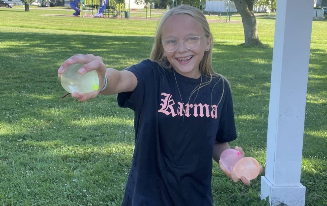 A young Bayshore community resident holds up a water balloon