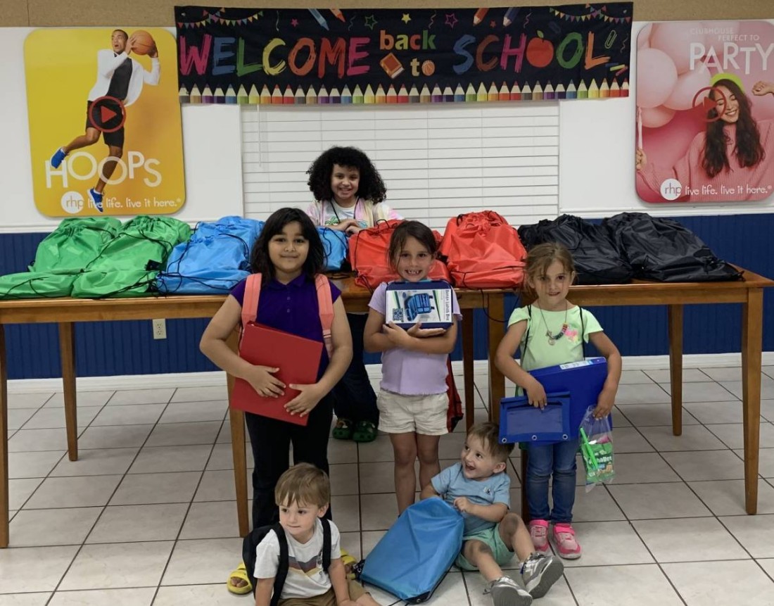 A group of small children holding new school supplies from the Bayshore school supply giveaway