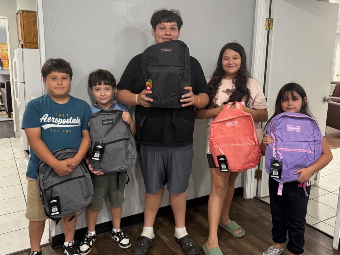 A group of children at a Bayshore manufactured home community show off their new backpacks