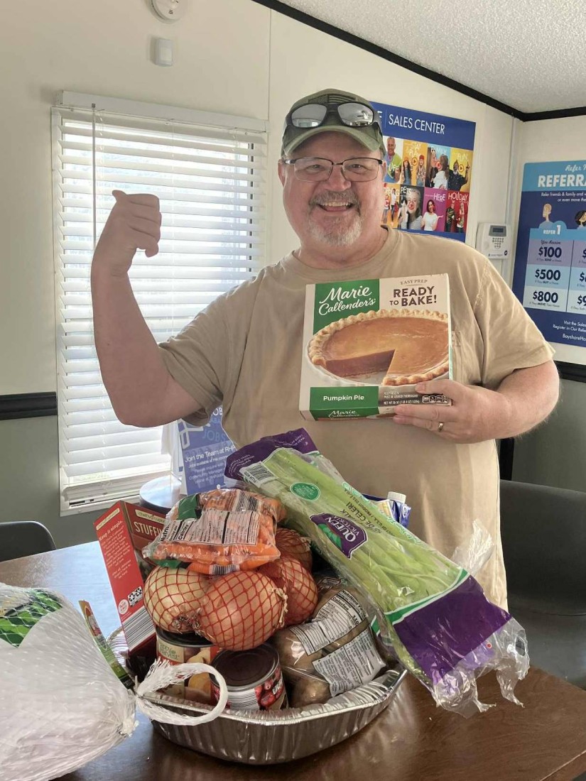 A Turkey Dinner Giveaway winner posing with the Thanksgiving dinner supplies he won