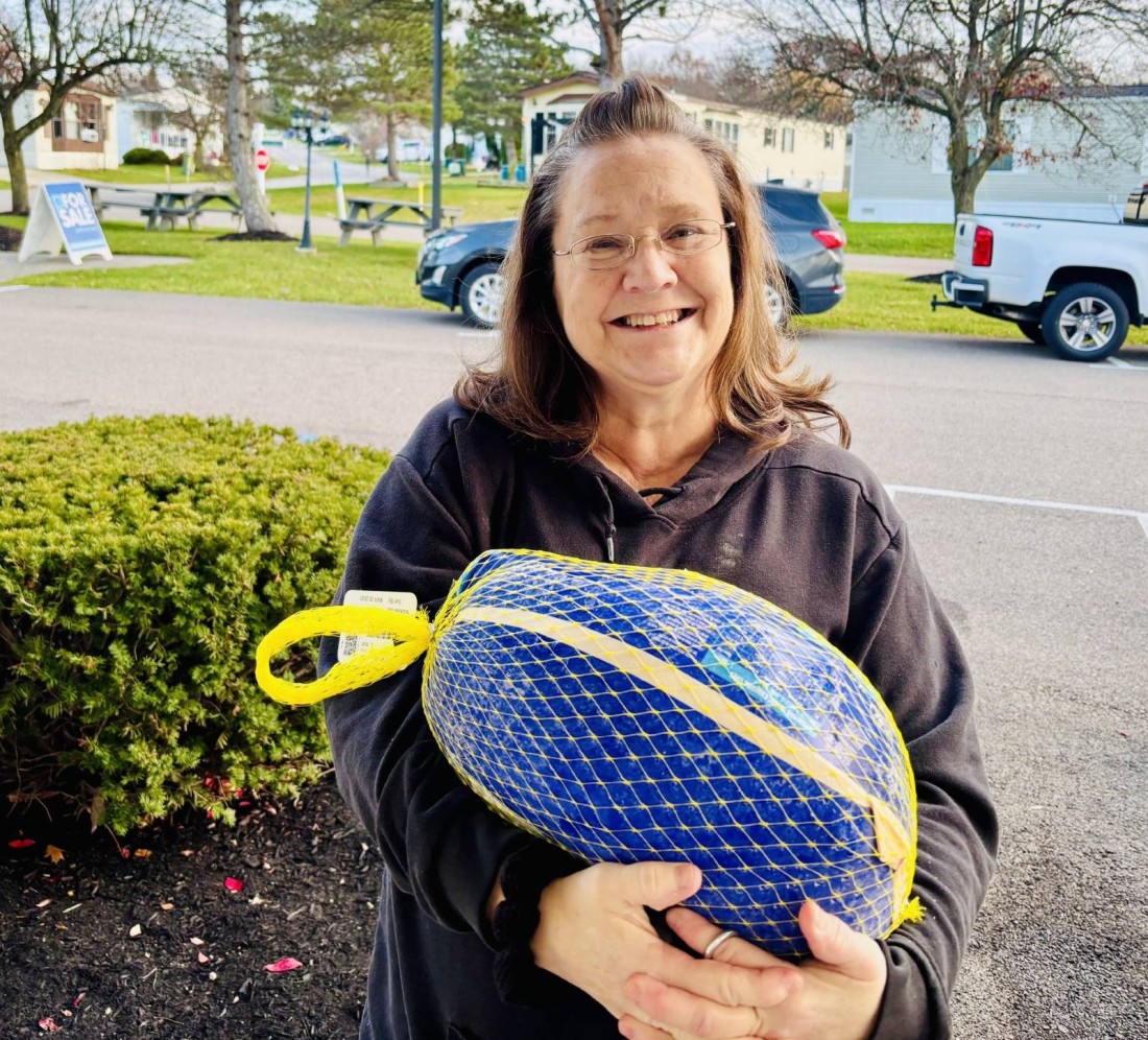 A Turkey Dinner Giveaway winner poses outside with the turkey she won