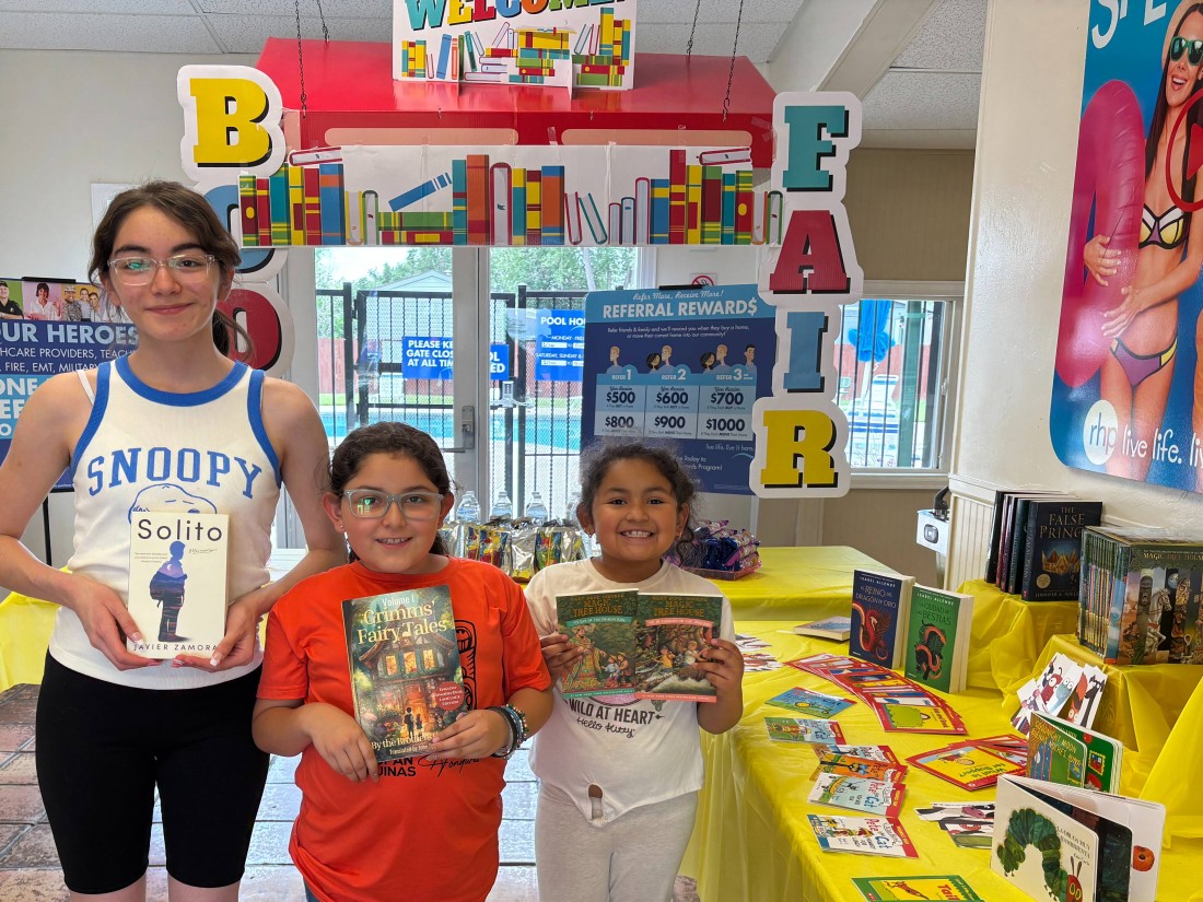 Children hold up their books at a book fair hosted at a Bayshore manufactured home community