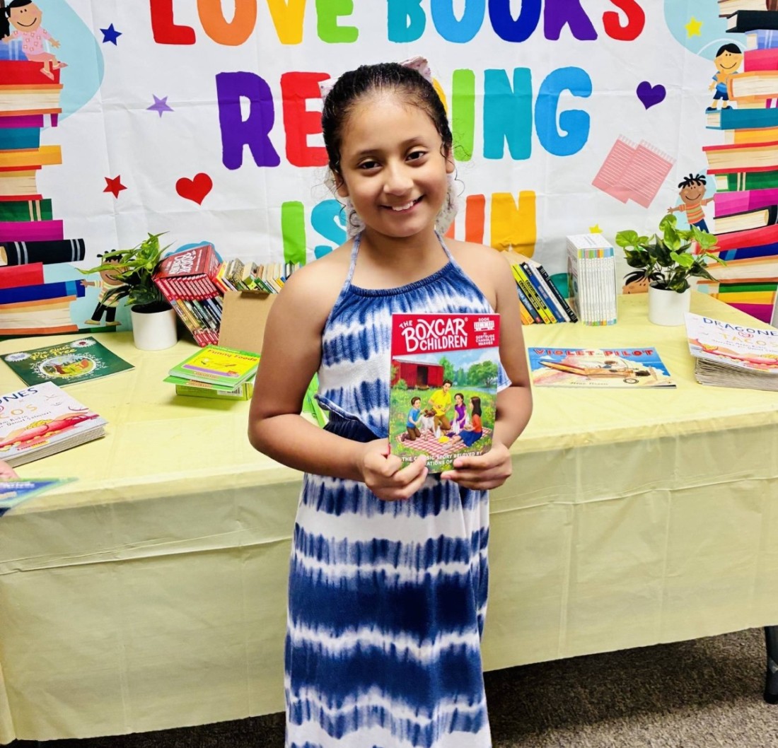 A young girl with a Boxcar children book at a Bayshore manufactured home community's book fair