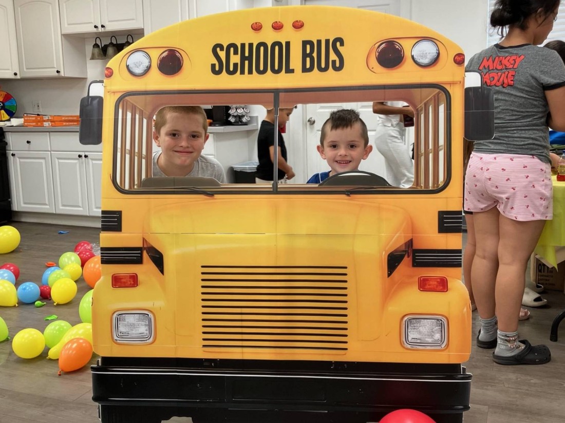 Kids posing with a school bus cutout on the first day of school at a Bayshore manufactured home community