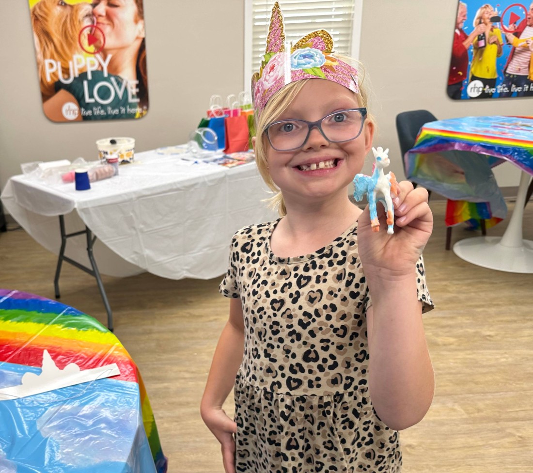 A young girl holds up her unicorn craft to go with her manufactured home community's summer reading event