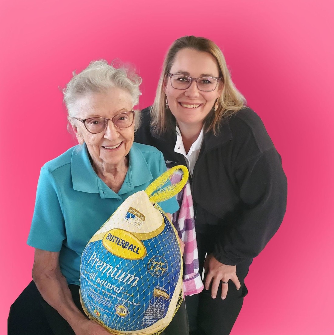 senior woman and caregiver posing for a picture and holding a Butterball turkey