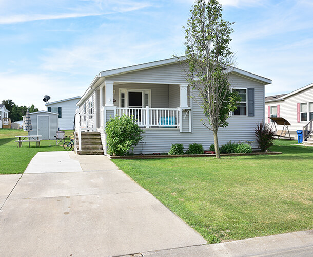 a manufactured home with paved drive and parking space and a nice front porch