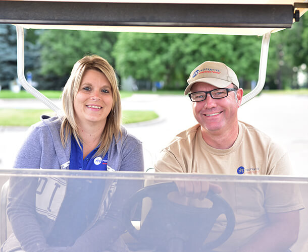a woman and man smiling and sitting together on a golf cart