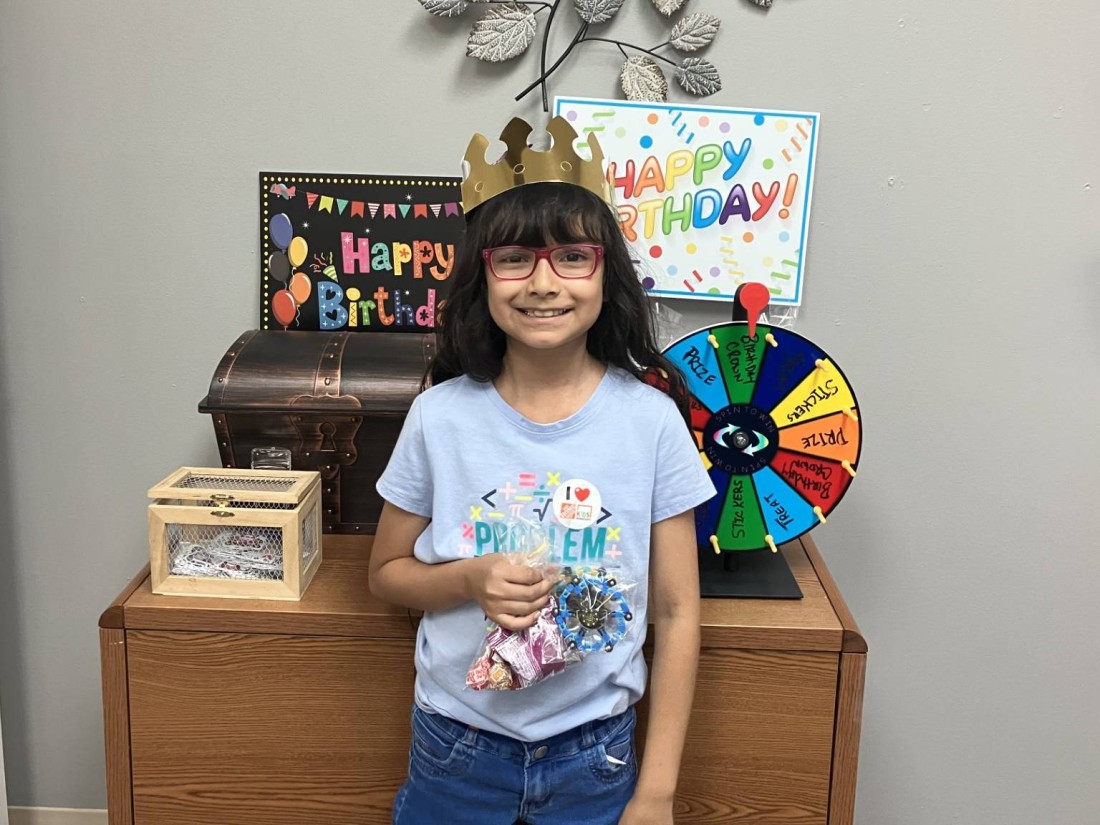 A child with her birthday spin and win swag, including birthday crown and goodie bag