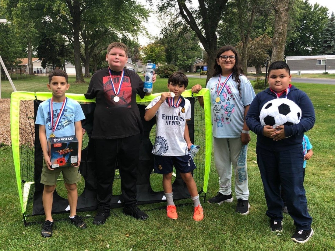 Kids pose with their medals and prizes in front of a soccer goal at a 2025 Kickin’ It Challenge hosted by RHP Social