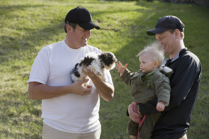 Neighbors with a puppy and a baby interact on a walk in their manufactured home community