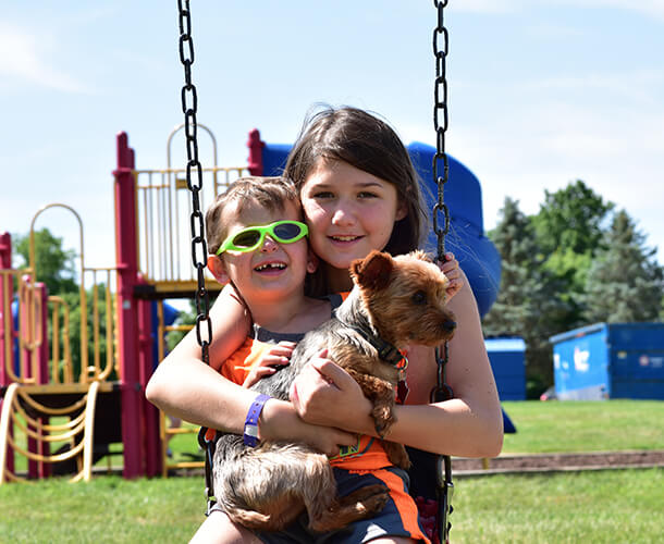 kids and a dog on a swing in a community park playground